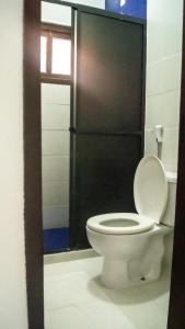 a bathroom with a white toilet with a black door at Pousada Estalagem Vila Tania in Itaúnas