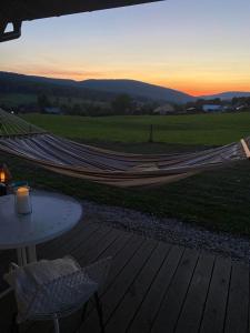 eine Hängematte auf einer Terrasse mit einem Tisch und einem Sonnenuntergang in der Unterkunft Niedźwiedziówka Bartne in Bartne