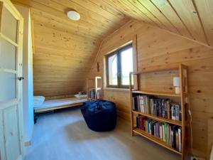 eine Blockhütte mit einem Bücherregal und einem Fenster in der Unterkunft Niedźwiedziówka Bartne in Bartne