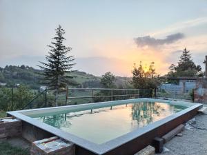 uma piscina com um pôr-do-sol ao fundo em cascina carlo em Aie