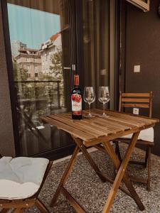 Elegant Escape apartment I - City Centre في براتيسلافا: زجاجة من النبيذ موضوعة على طاولة خشبية مع كأسين من النبيذ
