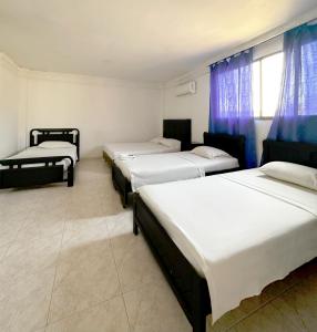 three beds in a room with blue curtains at Hotel Costa Caribe in Barranquilla