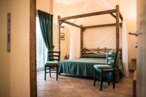 a bedroom with a canopy bed and two chairs at Tenuta Valdelmelo in Castiglione della Pescaia