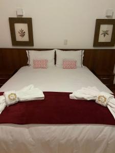 1 dormitorio con 1 cama con 2 toallas en Hotel Pousada Bella Locanda, en Campos do Jordão