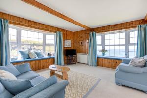 a living room with blue furniture and windows at Gulland in Port Isaac