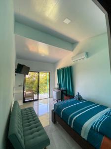 een slaapkamer met een bed, een bank en een raam bij Ocean's Breeze Apartment and Rooms in Puerto Viejo