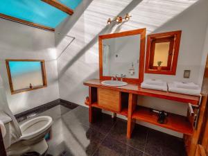 a bathroom with a sink and a mirror and a toilet at Ecolodge K'arasirca in Comunidad Yumani