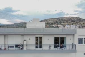 a white building with a balcony with a mountain in the background at Casa Karma in Volos