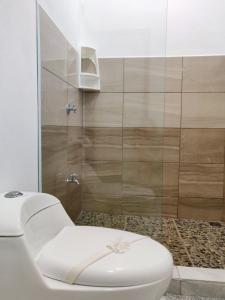 a white toilet in a bathroom with a shower at Ocean's Breeze Apartment and Rooms in Puerto Viejo