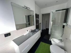 W łazience znajduje się umywalka, toaleta i lustro. w obiekcie Home Stella w mieście Pietra Ligure