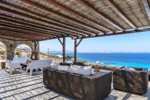 un patio al aire libre con muebles de mimbre y el océano en Salty Blè, en Agios Ioannis Mykonos