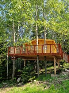 a tree house with a deck in the woods at Treehouse Podpoľanie in Detvianska Huta