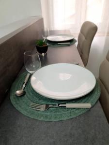 een tafel met twee witte platen en een vork en mes bij Cocon Cosy in Clermont-Ferrand
