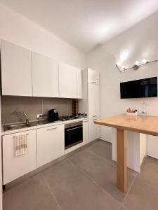 a kitchen with white cabinets and a wooden table at Casa Clementina in Pisa