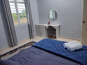 Schlafzimmer mit einem blauen Bett, einem Schreibtisch und einem Fenster in der Unterkunft Bella Homestay Perlis in Arau