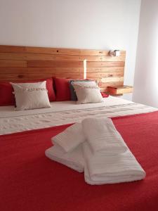 uma grande cama vermelha com lençóis brancos e almofadas em Casa Nera em Esquel