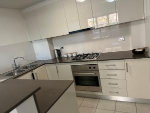 a kitchen with white cabinets and a stove top oven at Westmead Home away from home in Westmead
