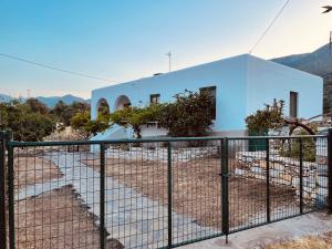 uma casa branca com uma cerca à frente. em Anevalousa Beach House em Moutsoúna