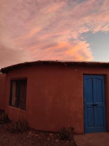 una casa con una puerta azul y un cielo nublado en Cabañas Rica-Rica Lodge, en San Pedro de Atacama