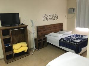 una camera con letto, TV e sedia di BIG HOTEL a Osório