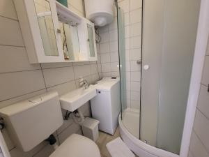 biała łazienka z toaletą i umywalką w obiekcie Apartment with patio 50m from the beach and Lungomare w mieście Opatija +15 zdjęć