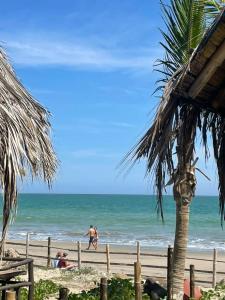 a beach with a palm tree and people on the beach at Mancora Sunset House in Máncora