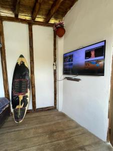 a room with a tv and a surfboard on the wall at Mancora Sunset House in Máncora