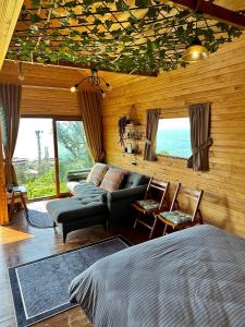 a bedroom with a bed and a couch and windows at Manzara dağevi in Rize