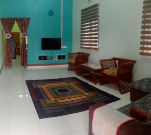 uma sala de estar com um sofá e uma televisão em Adilah Homestay A em Pasir Puteh