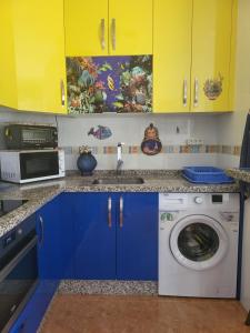 a kitchen with blue cabinets and a washing machine at Apartamento La Urba in Roquetas de Mar