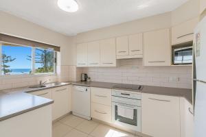 a kitchen with white cabinets and a large window at Kooringal Unit 10 in Gold Coast