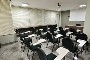 uma sala de aula com mesas e cadeiras e um quadro branco em Domus Hotel Cidade Nobre Ipatinga em Ipatinga