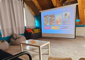 a large screen in a room with a couch and a table at Casa Gomez in Santa Cilia de Jaca