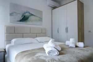 a white bedroom with a bed with towels on it at Fishta Quality Apartments Q5 36 in Velipojë