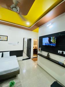 sala de estar con cama y TV de pantalla plana en SARDAR HOME STAY, en Garudeshwar
