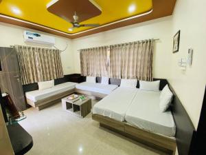 a bedroom with two beds and a couch at SARDAR HOME STAY in Garudeshwar