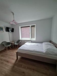 biała sypialnia z łóżkiem i oknem w obiekcie Pokoje Gościnne LENAILI w mieście Jarosławiec