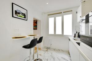 a white kitchen with a black chair in it at Charming and cozy at Parc des Buttes Chaumont in Paris