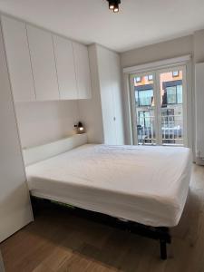 a white bed in a room with a window at Appart Noah SeaFront in Knokke-Heist