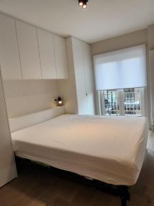 Cama blanca en habitación con 2 ventanas en Appart Noah SeaFront en Knokke-Heist
