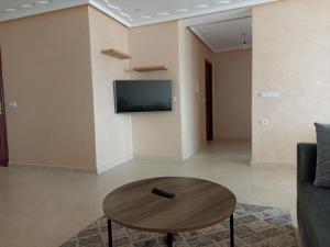ein Wohnzimmer mit Tisch und Fernseher in der Unterkunft Appartement familial au centre de Nador Ville in Nador