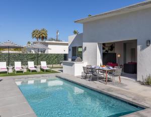 a house with a swimming pool and a table and chairs at Picture Perfect Retreat in Palm Springs