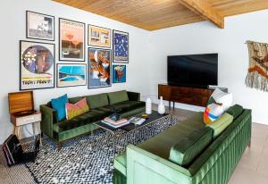 a living room with two green couches and a flat screen tv at Mid Century Mood House in Palm Springs