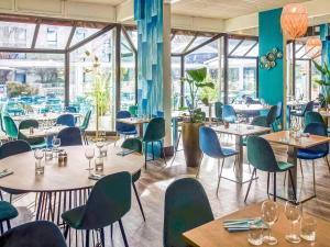 um restaurante com mesas, cadeiras e janelas em Novotel Marseille Est Porte d'Aubagne em Marselha