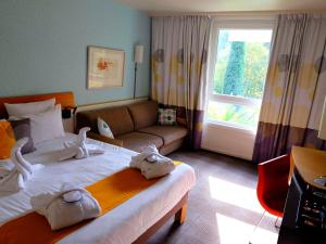 um quarto de hotel com uma cama grande e um sofá em Novotel Marseille Est Porte d'Aubagne em Marselha