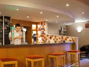 un homme debout derrière un bar dans un restaurant dans l'établissement ibis Chesterfield Centre – Market Town, à Chesterfield