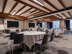 a conference room with tables and chairs and a screen at Novotel Amsterdam City in Amsterdam