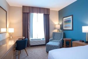 スコーミッシュにあるSandman Hotel and Suites Squamishのベッド、デスク、椅子が備わるホテルルームです。