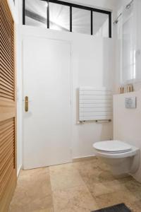 La salle de bains blanche est pourvue de toilettes et d'une fenêtre. dans l'établissement Appartement type loft - 40m² Marais, à Paris