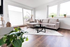 ein Wohnzimmer mit einem Sofa und einem Tisch in der Unterkunft SmartFewo - Das Penthouse - BBQ - Balkon - Parkplatz in Bad Zwischenahn